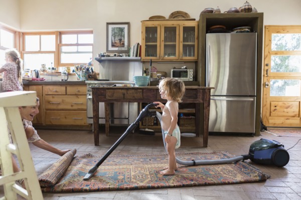 Caucasian brother and sister vacuuming rug