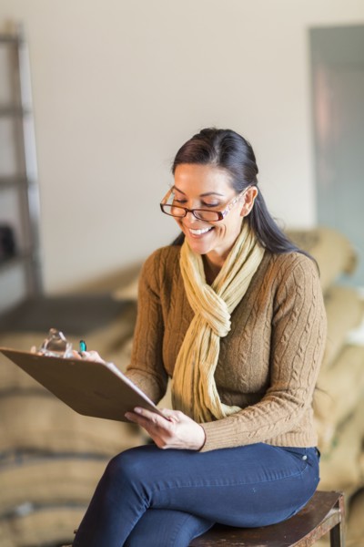 Hispanic woman writing on clipboard