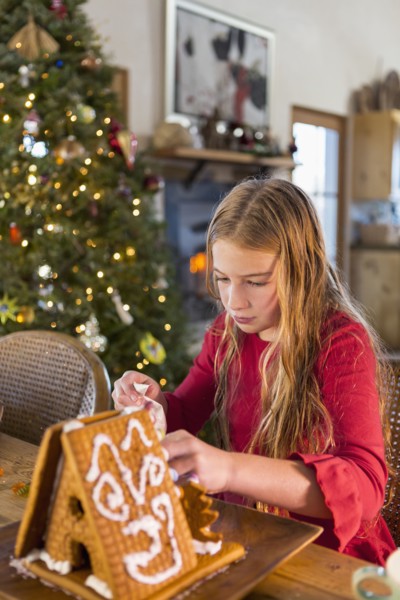 Caucasian girl decorating gingerbread house