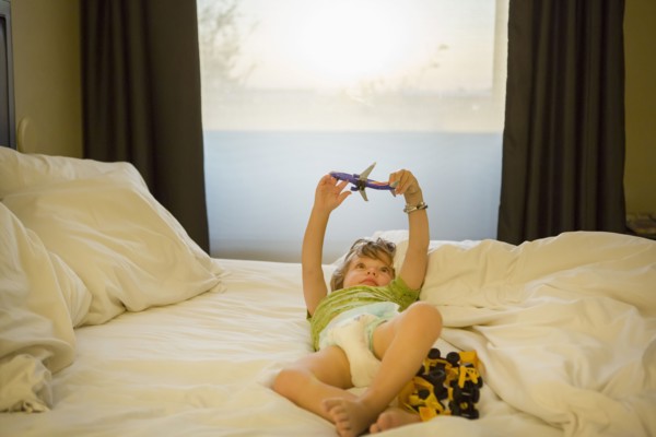 Caucasian boy playing with airplane on bed