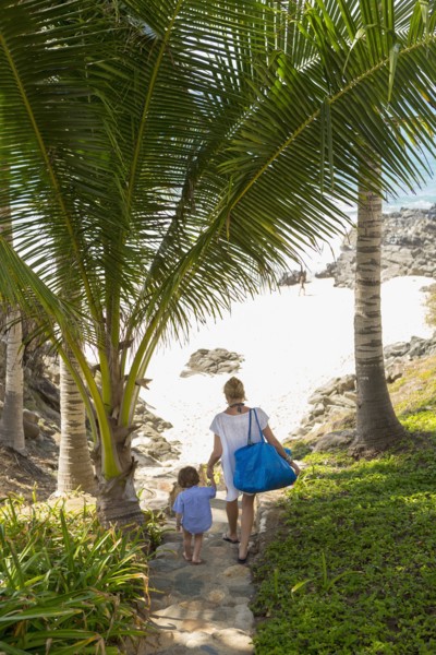 Caucasian mother and sun descending staircase to beach