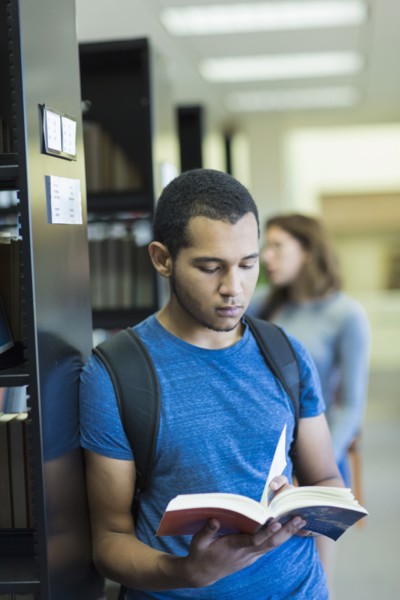 Mixed Race boy reading book in library
