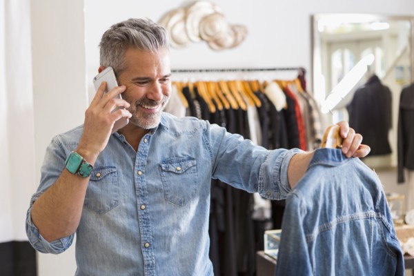 Caucasian man examining shirt talking on cell phone