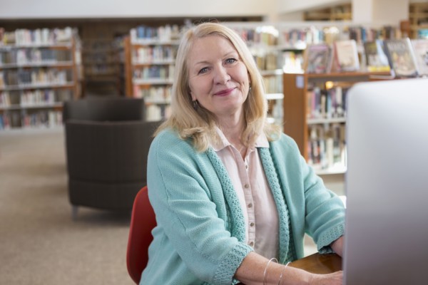 Smiling Caucasian woman using computer in library