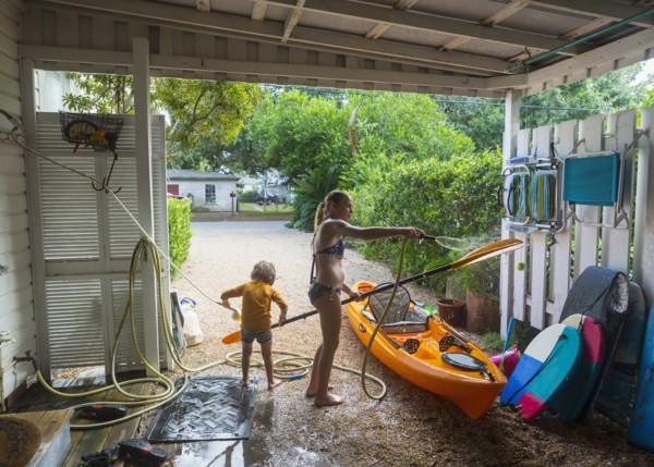 Caucasian brother and sister rinsing kayak with hose