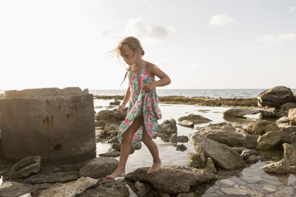 Caucasian girl walking on rocks at beach
