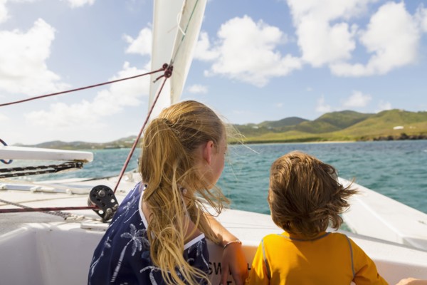 Wind blowing hair of Caucasian brother and sister in sailboat