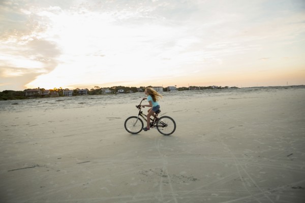 Caucasian girl riding bicycle on beach