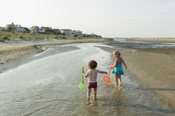Caucasian brother and sister carrying nets on beach