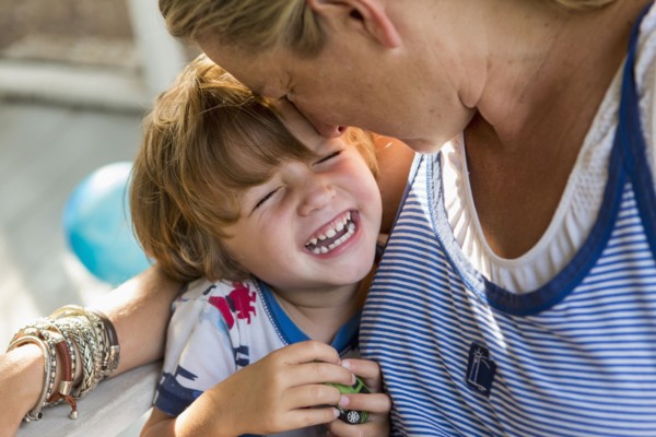 Caucasian mother hugging laughing son holding toy car