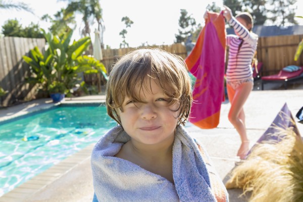 Caucasian boy wrapped in towel near swimming pool