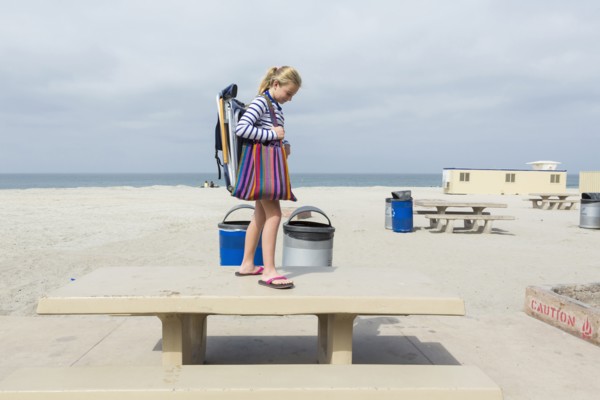 Caucasian girl standing on picnic table at beach