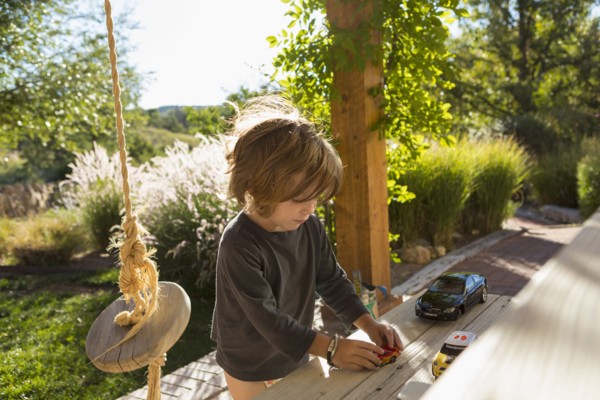 Caucasian boy playing with toy cars on patio