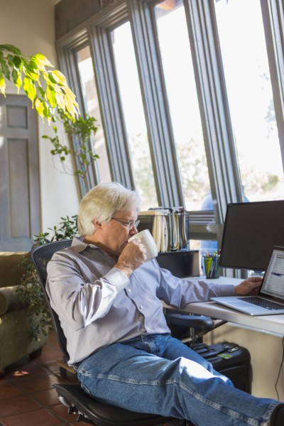 Caucasian man drinking coffee and using laptop