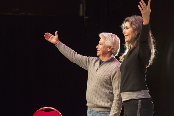 Hispanic man and woman with arms raised on theater stage