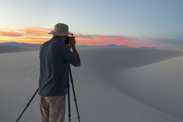 Caucasian man photographing desert at sunset