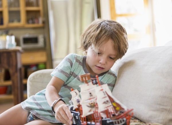 Caucasian boy sitting on sofa playing with toy boat