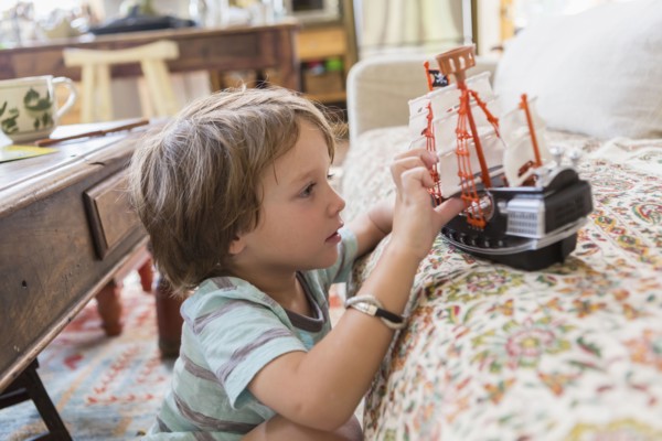 Caucasian boy playing with toy boat on sofa