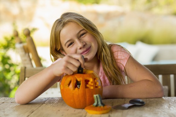 Portrait of smiling Caucasian girl with carved pumpkin
