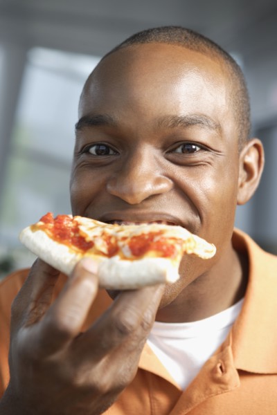 Close up of African man eating pizza