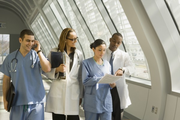 Multi-ethnic doctors and nurses reviewing paperwork in corridor