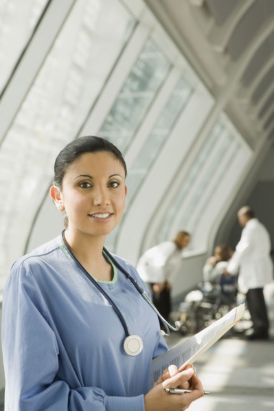 Hispanic nurse holding medical chart in corridor