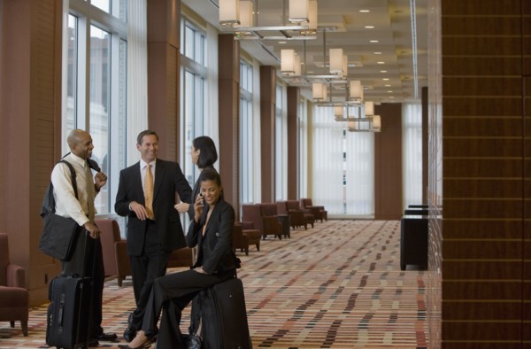 Multi-ethnic business people with suitcases talking in lobby
