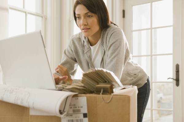 Hispanic woman using laptop on boxes
