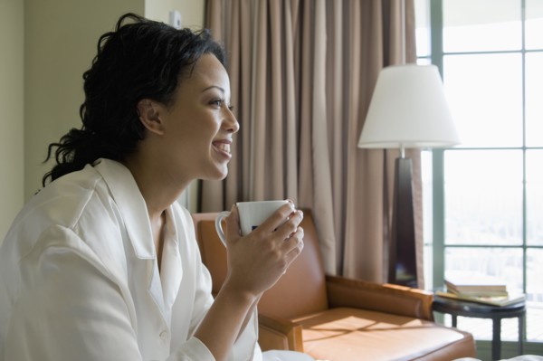 African woman drinking coffee in bedroom