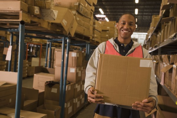 Black man carrying box in warehouse