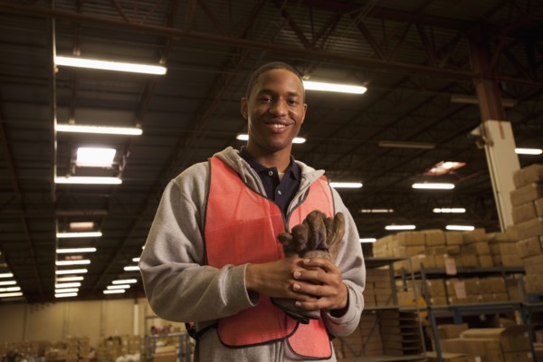 Black man in reflector-vest in warehouse