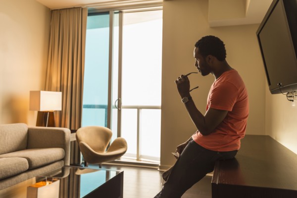 Black man leaning on credenza in living room