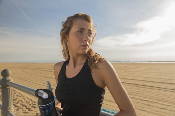 Caucasian teenage girl leaning on railing at beach