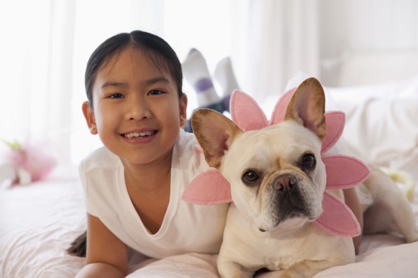 Asian girl laying on bed with costumed dog
