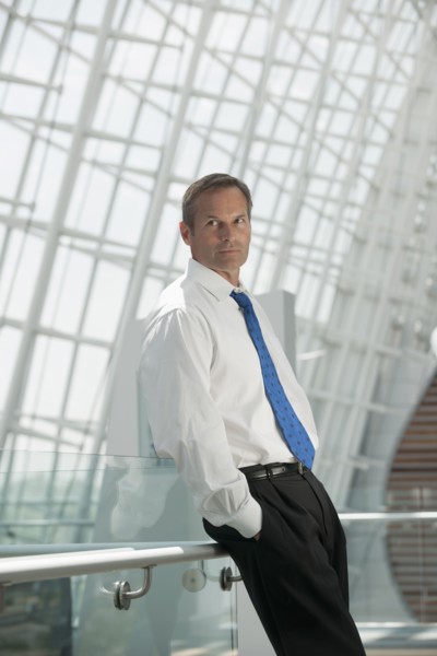 Caucasian businessman leaning on railing with hands in pockets