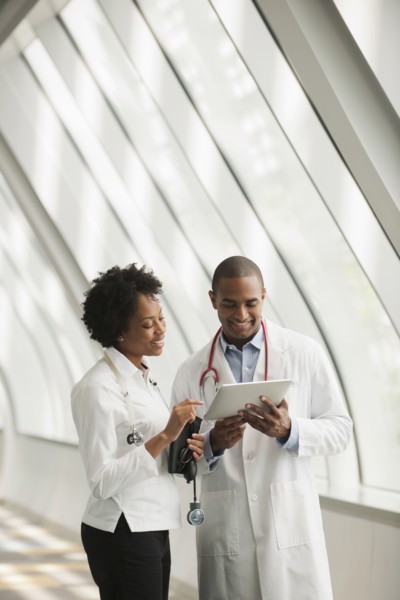 Doctors using digital tablet in hospital corridor