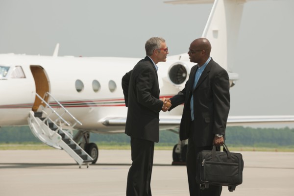 Businessmen shaking hands on airport tarmac