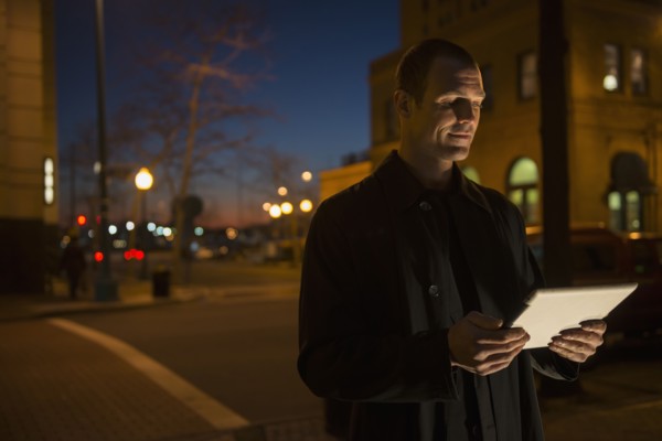 Caucasian man using tablet computer on city street
