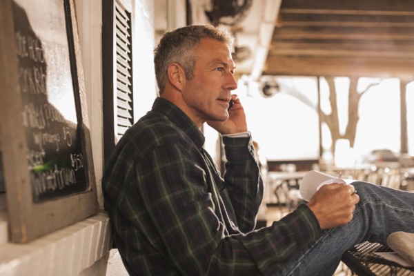 Caucasian man talking on cell phone on patio