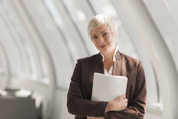 Caucasian businesswoman carrying papers in lobby