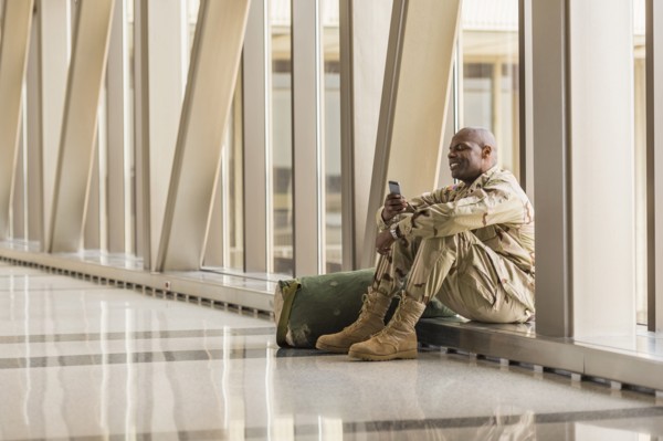African American soldier using cell phone in airport