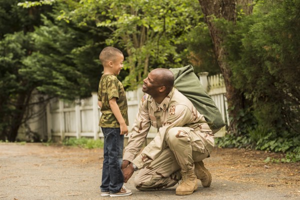 African American soldier tying shoelace for son