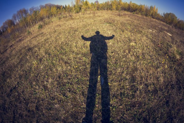 Fish-eye lens view of shadow of man in field