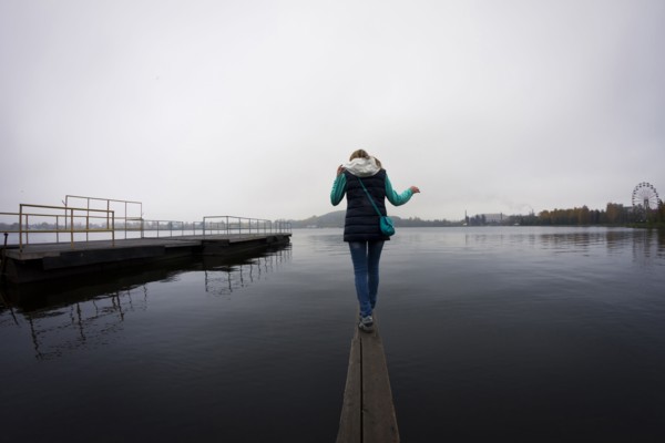 Caucasian woman balancing on dock over still lake