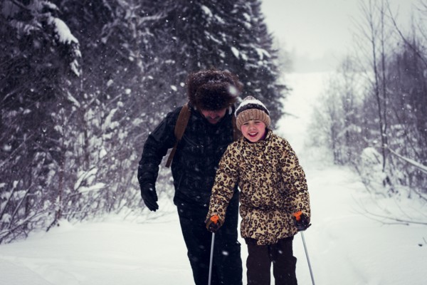 Caucasian father and daughter cross-country skiing on snowy road