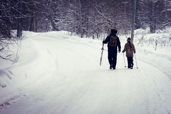 Caucasian father and daughter cross-country skiing on snowy road