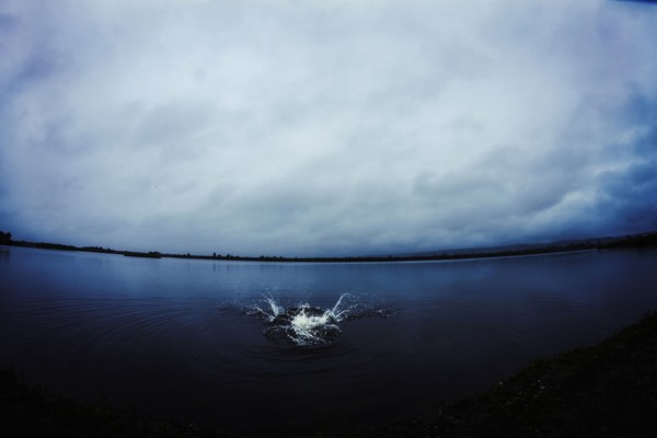 Caucasian man splashing in still remote lake