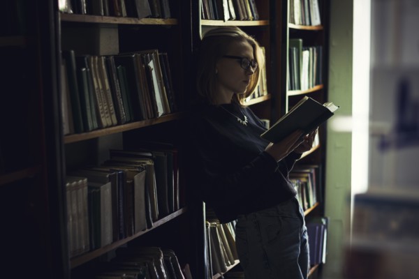Caucasian woman reading book in library