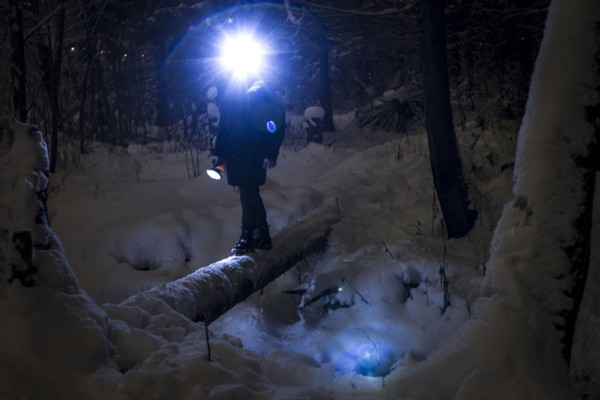 Caucasian hiker wearing headlamp balancing on forest log