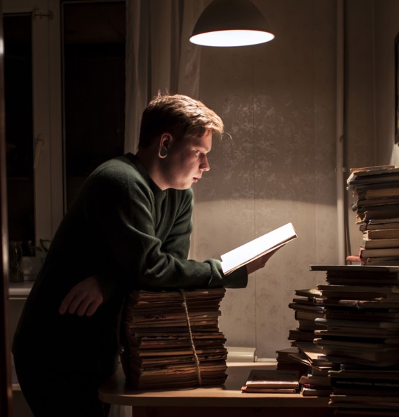 Caucasian man reading stack of books